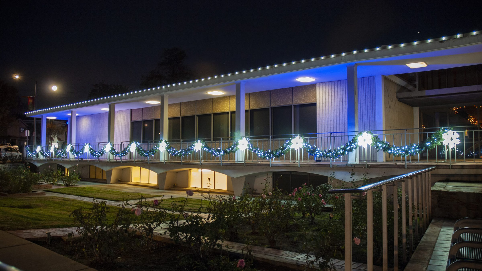 Office campus lit with roofline lights and garland at night