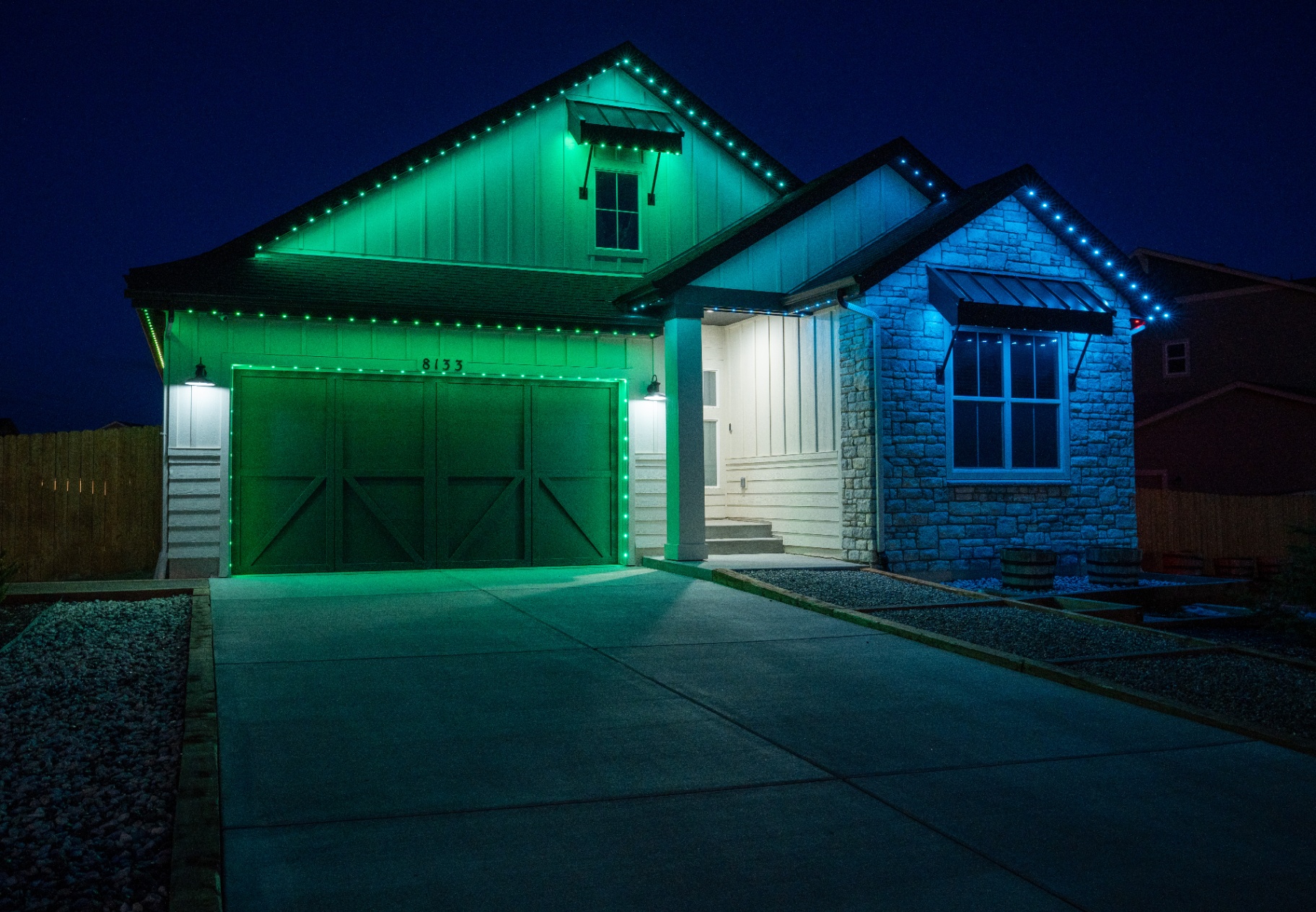 Home illuminated with green and blue permanent LED lighting at night