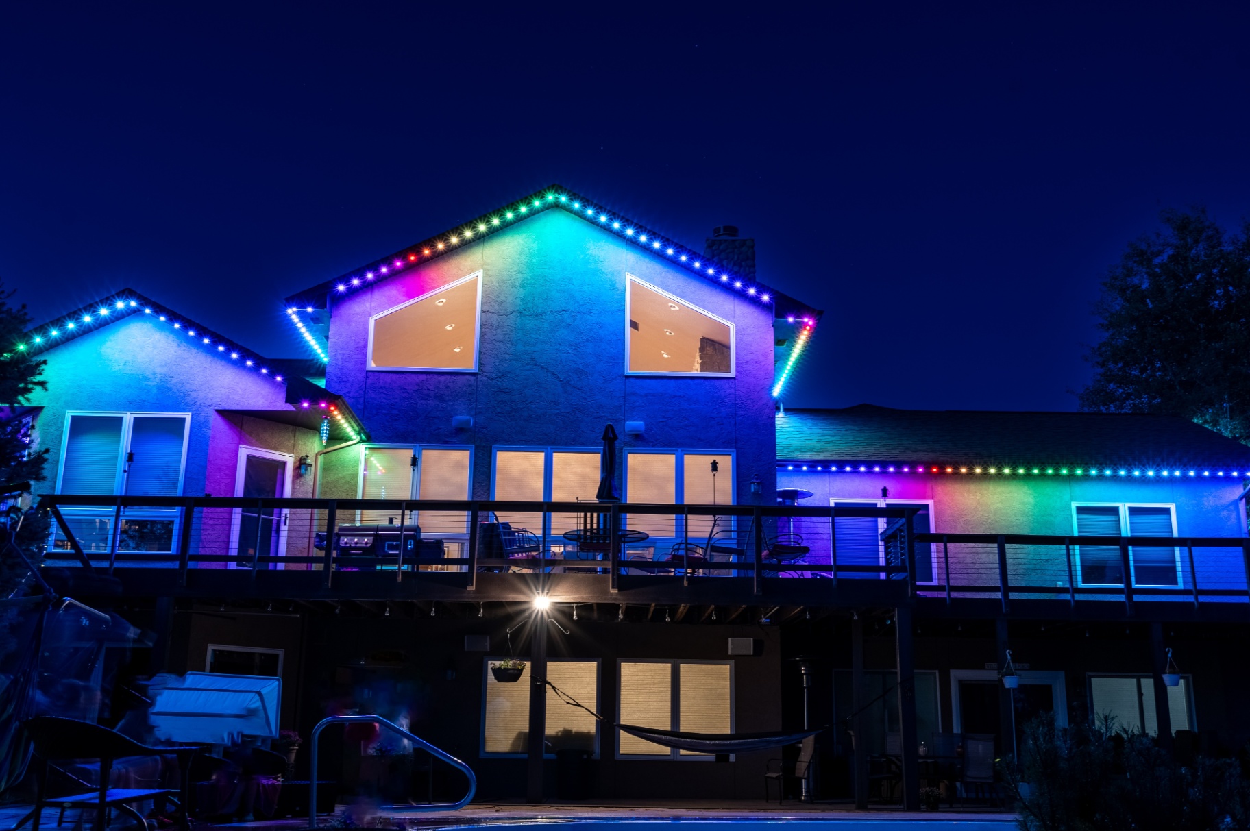 Full rainbow lighting across a large two-story home at dusk